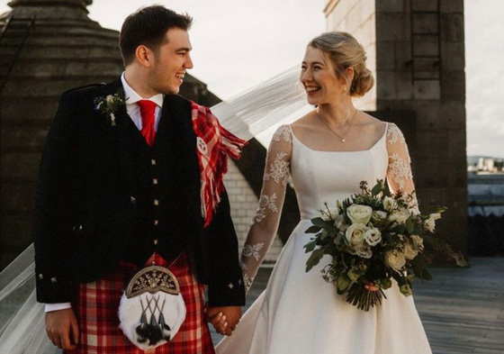 Bride and groom smile at each other with matching bouquet and buttonhole